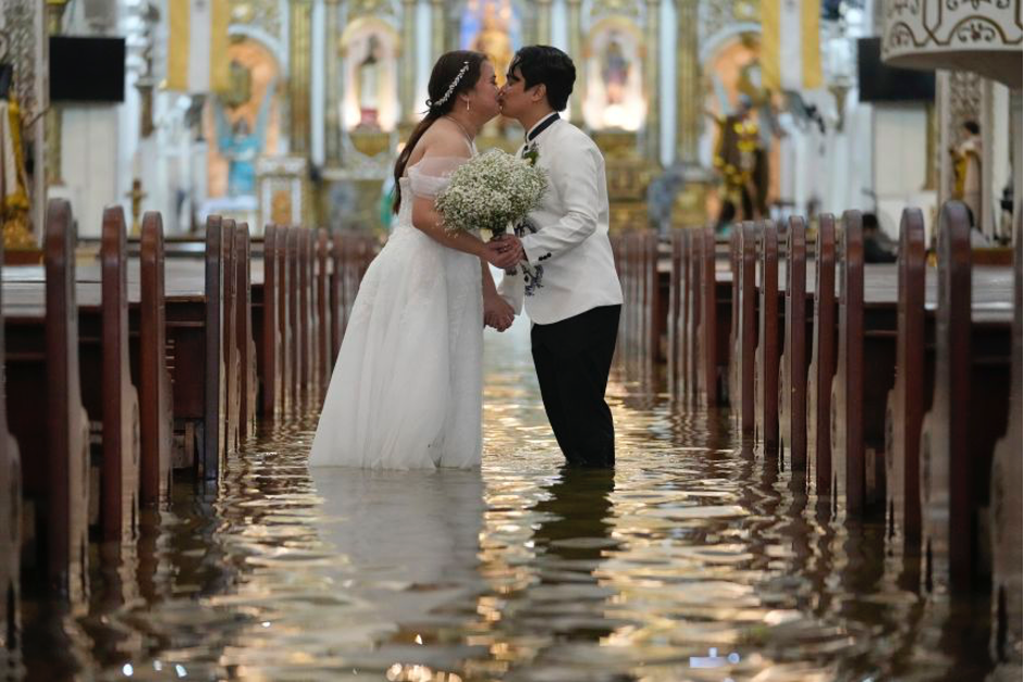 Newlyweds Jade Rick Verdillo right, and Jamaica kiss during their wedding at the flooded Barasoain church in Malolos, Bulacan province, Philippines on Tuesday, July 22, 2025. Aaron Favila/AP